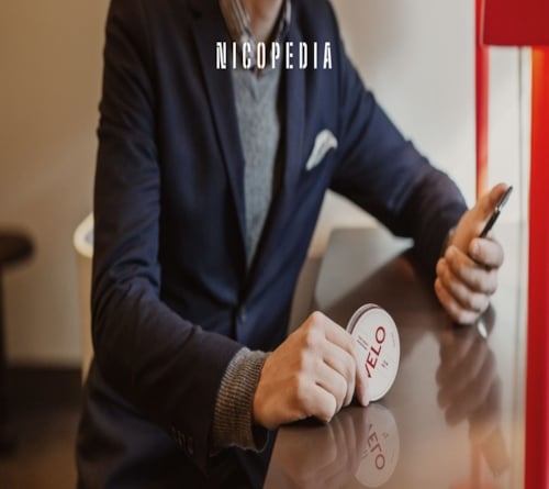 Mann sitzt mit einer Snus-Dose in der Hand in einem Café