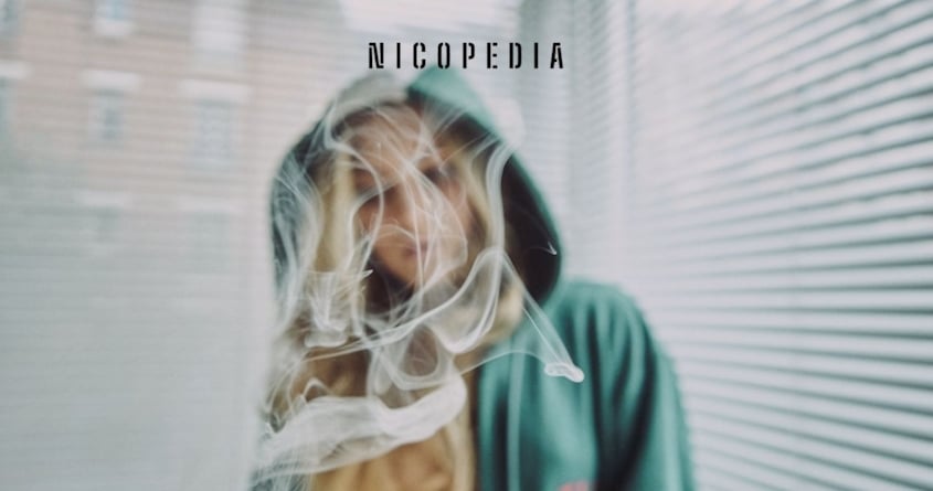 Eine Frau mit Kapuze in einer Rauchwolke, die eventuell immer wieder unter Nikotinentzug leidet. 