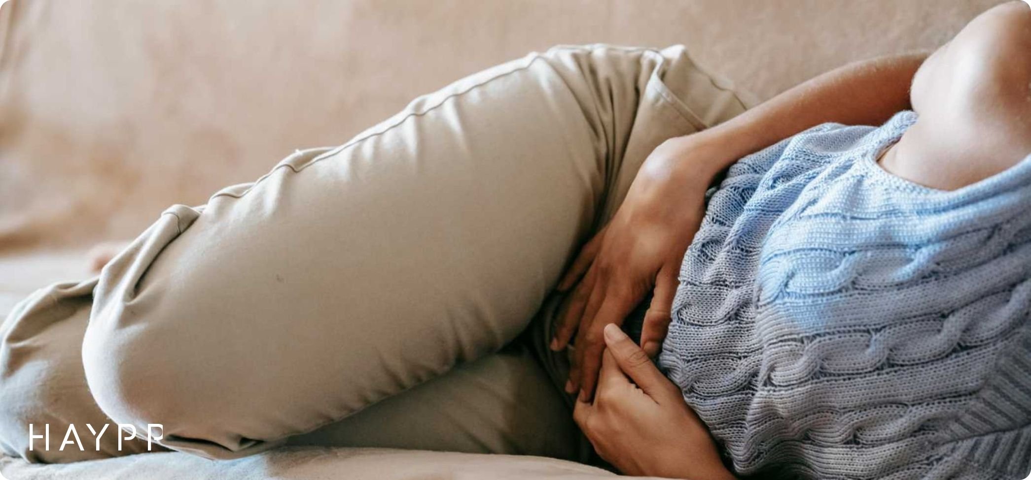 A woman holding down lying her stomach; one of the symptoms of nicotine poisoning