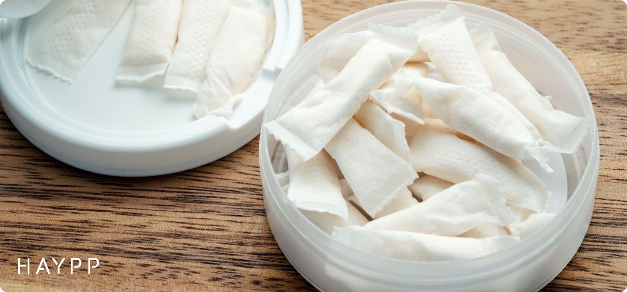 Open nicotine pouch can on wooden surface