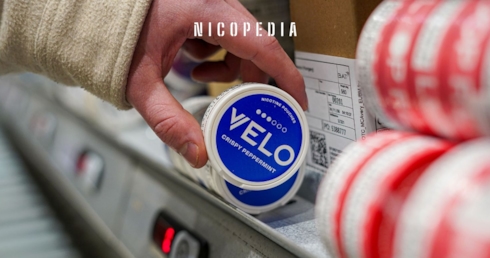 A person picks up a VELO nicotine pouch can