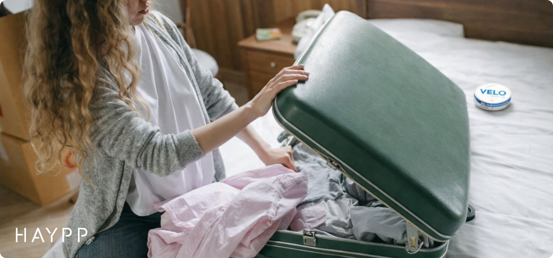 Woman packs suitcase with nicotine pouch can on the side