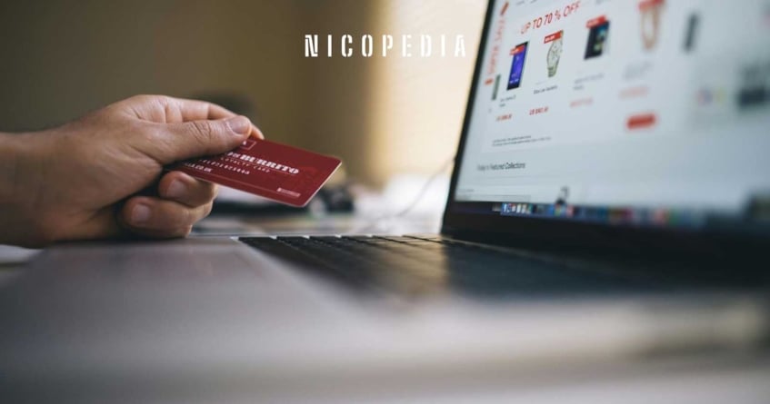 hand with credit card next to a laptop screen showing online shop